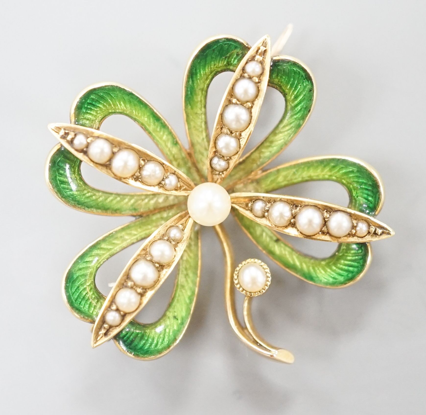 An Edwardian 15ct, seed pearl and green enamel set clover brooch, with later bale attachment, width 24mm, gross weight 4.4 grams.